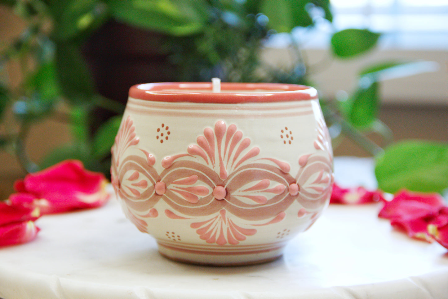 side view of an Artisanal candle in a beautiful light pink and biege handmade design talavera cup with a handle. Handcrafted by Artisan in Puebla, Mexico. 100% All Natural Soy Candle. Reuse the talavera as home decor or storage.