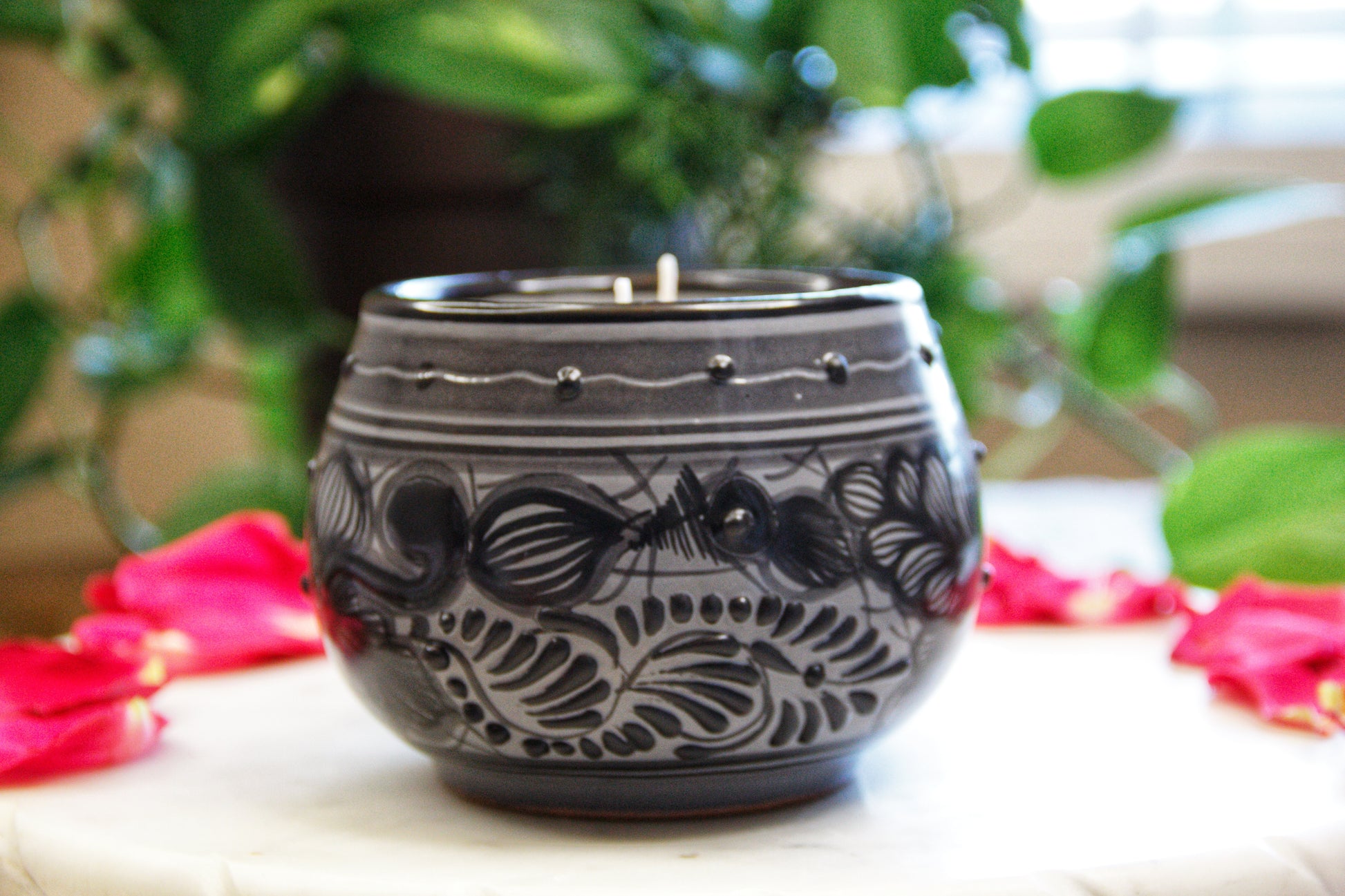 side view of an Artisanal candle in a beautiful black and grey handmade flower design talavera cup with handle. Handcrafted by Artisan in Puebla, Mexico. 100% All Natural Soy Candle. Reuse the talavera as home decor or storage.