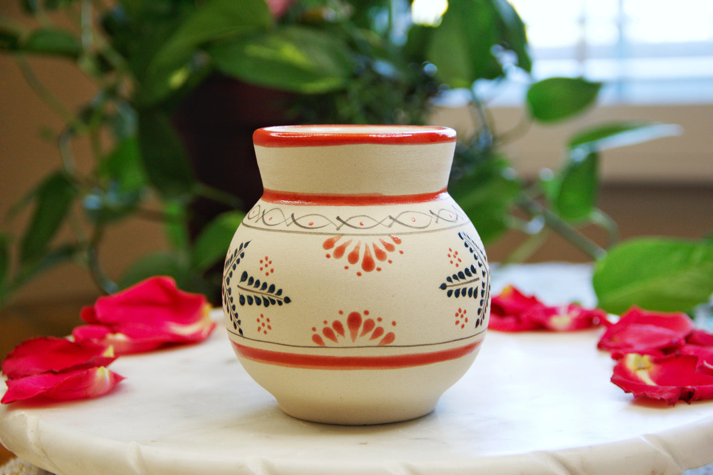 side view of a handmade artisanal candle in a red floral design mug. Custom made by Artisan in Mexico. 100% All Natural Soy Candle. Reuse the talavera as home decor or storage
