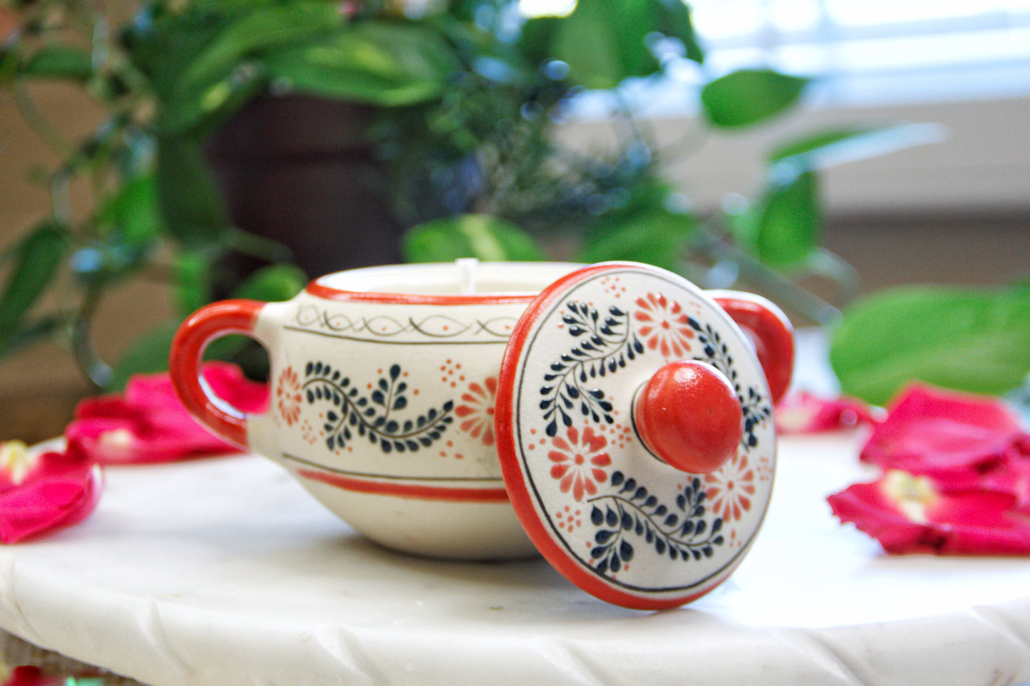 Front view of the handmade artisanal candle in a red floral design talavera with handles on both sides and an open lid. Custom made by Artisan in Mexico. 100% All Natural Soy Candle. Reuse the talavera as home decor or storage.