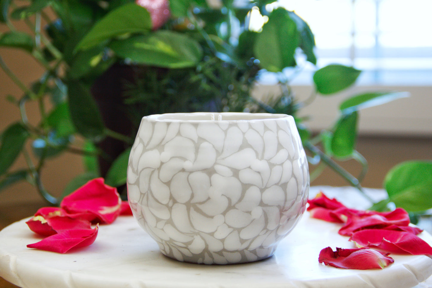 side view of an Artisanal candle in a beautiful handmade white strokes design talavera cup with handle. Handcrafted by Artisan in Puebla, Mexico. 100% All Natural Soy Candle. Reuse the talavera as home decor or storage.