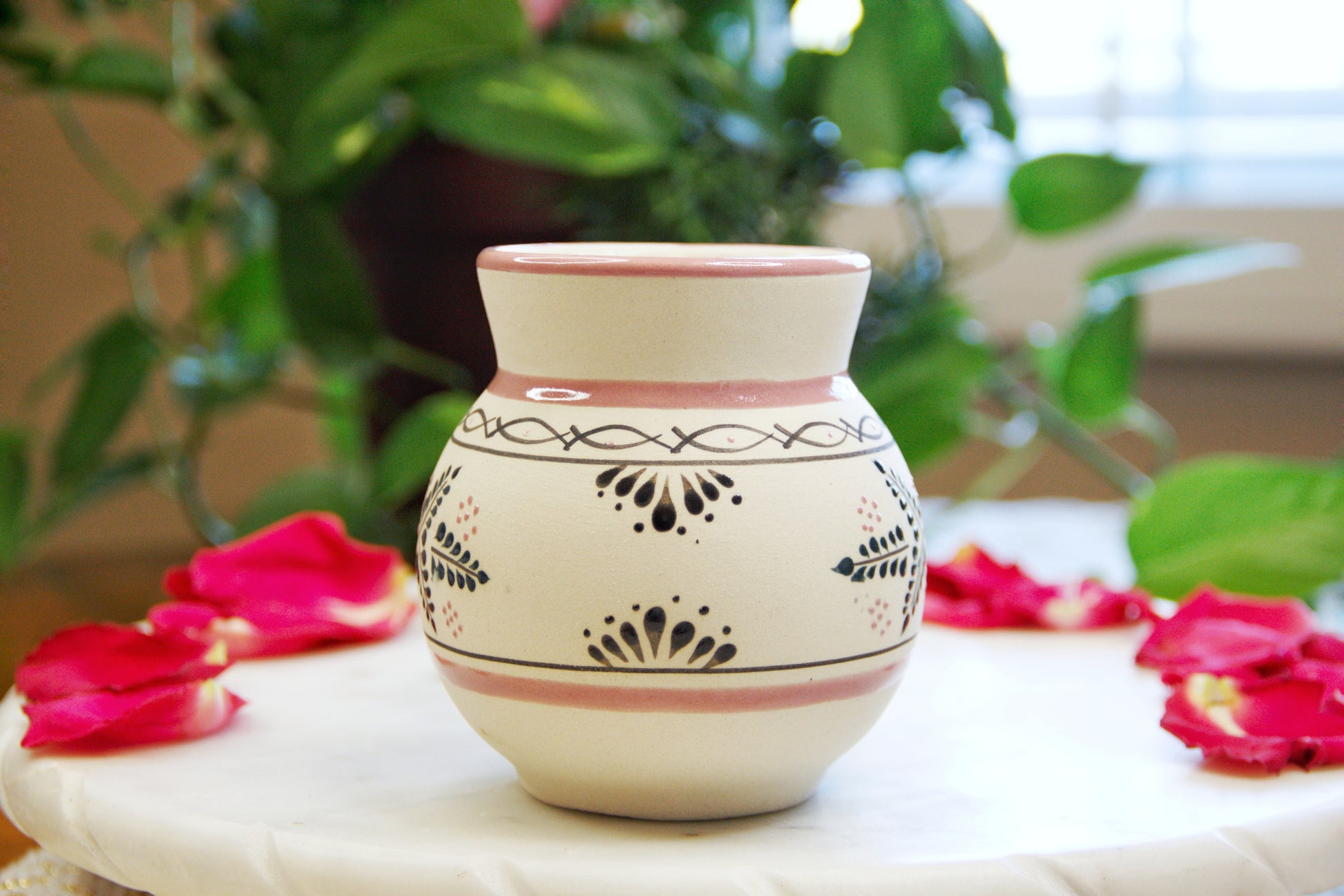 side view of a handmade artisanal candle in a red floral design mug. Custom made by Artisan in Mexico. 100% All Natural Soy Candle. Reuse the talavera as home decor or storage