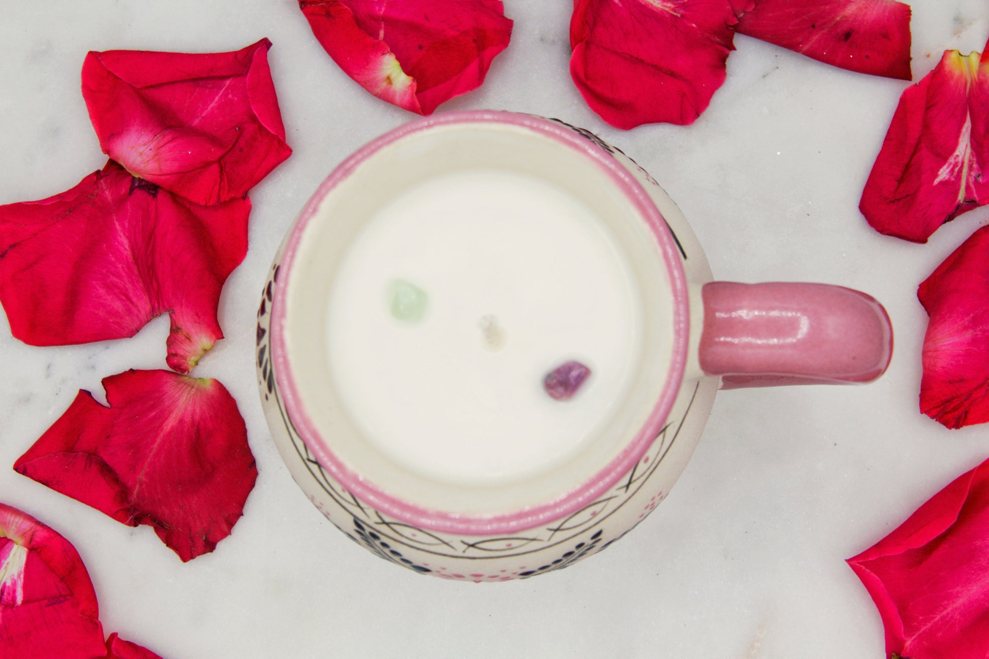 top view of a handmade artisanal candle in a pink floral design mug with a handle. Custom made by Artisan in Mexico. 100% All Natural Soy Candle. Reuse the talavera as home decor or storage