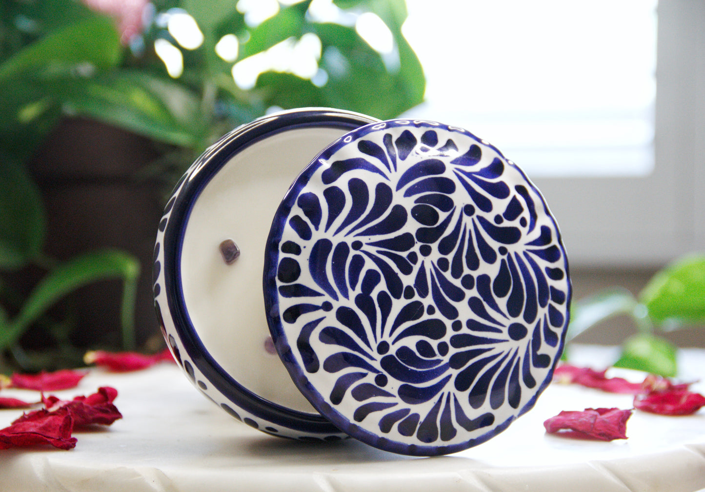 Side view of the Artisanal candle in a partial open lid beautiful talavera with hand made blue strokes design. Handcrafted by Artisan in Puebla, Mexico. 100% All Natural Soy Candle. Reuse the talavera as home decor or storage.