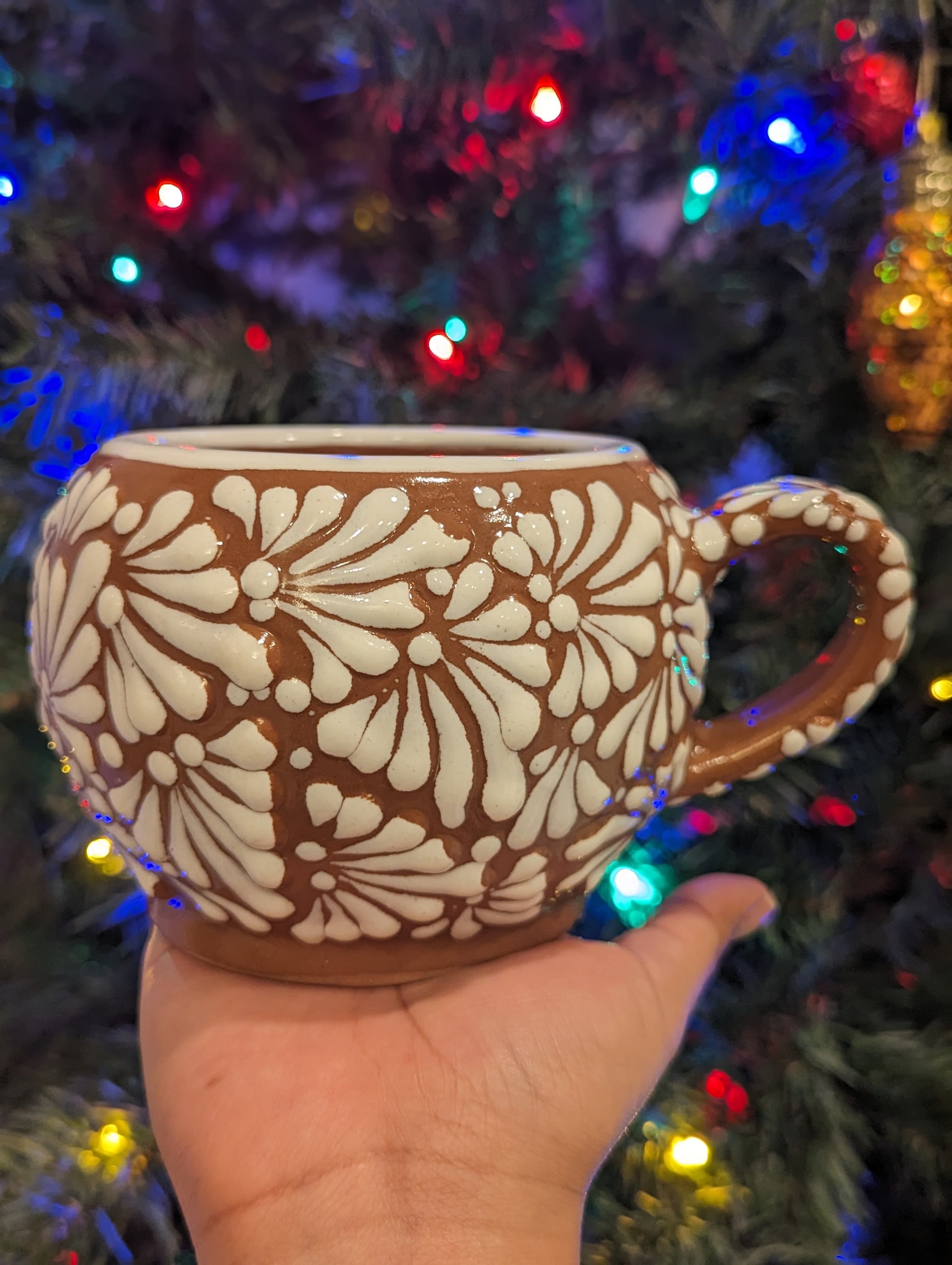 Artisanal candle in a beautiful brown cup with handle placed on a hand. Handmade white paint strokes design. Handcrafted by Artisan in Puebla, Mexico. 100% All Natural Soy Candle. Reuse the talavera as home decor or storage.