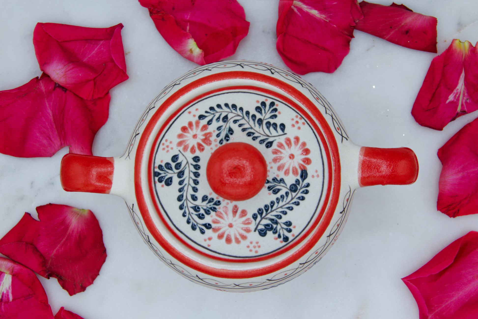 Top view of the handmade artisanal candle in a red floral design talavera with handles on both sides and a closed lid. Custom made by Artisan in Mexico. 100% All Natural Soy Candle. Reuse the talavera as home decor or storage.