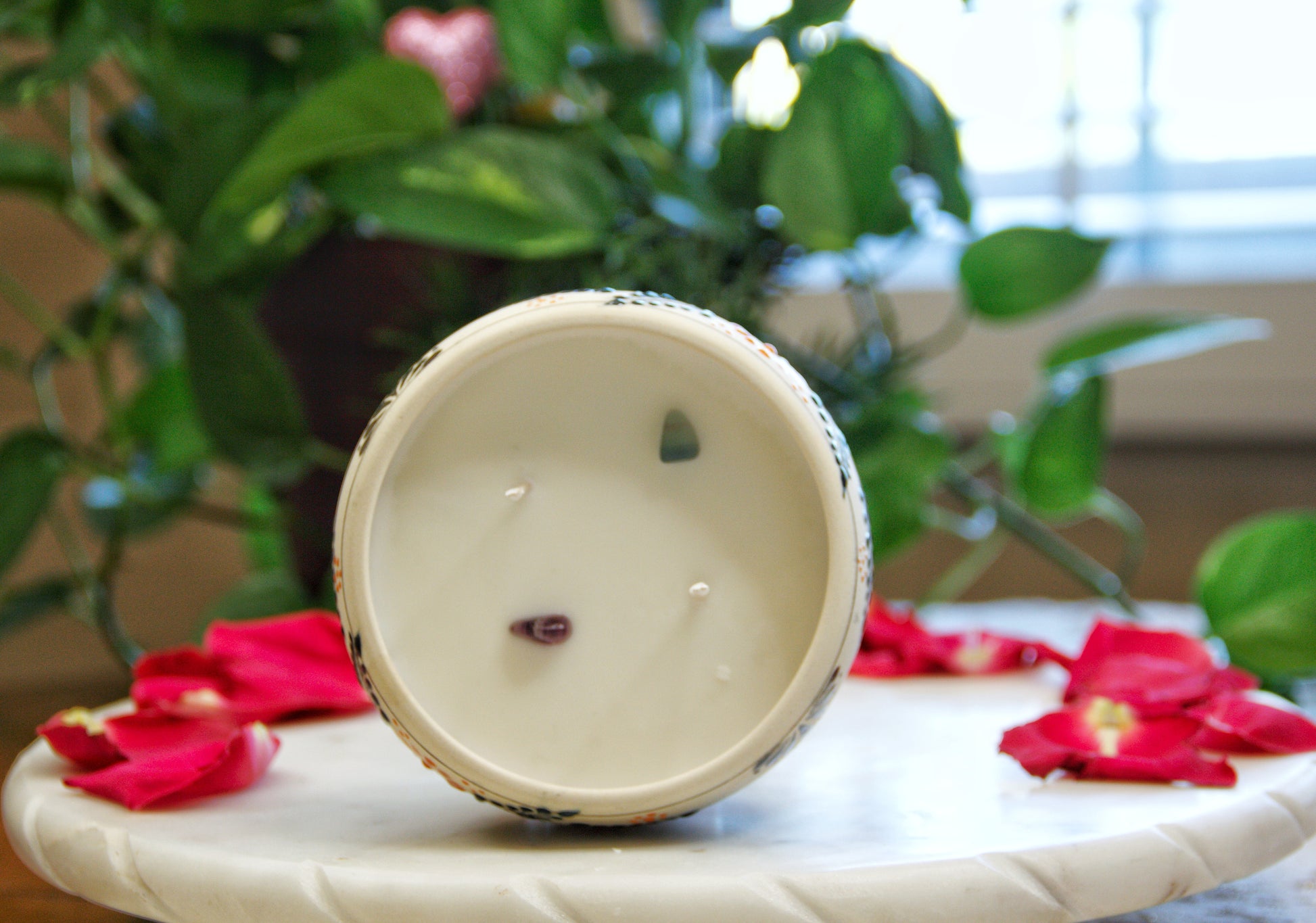 top view of a handmade artisanal candle in an orange floral design talavera. Custom made by Artisan in Mexico. 100% All Natural Soy Candle. Reuse the talavera as home decor or storage