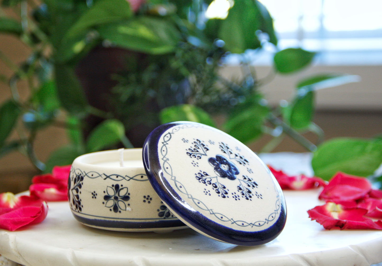 handmade artisanal candle in a blue floral design talavera with an open lid. Custom made by Artisan in Mexico. 100% All Natural Soy Candle. Reuse the talavera as home decor or storage.