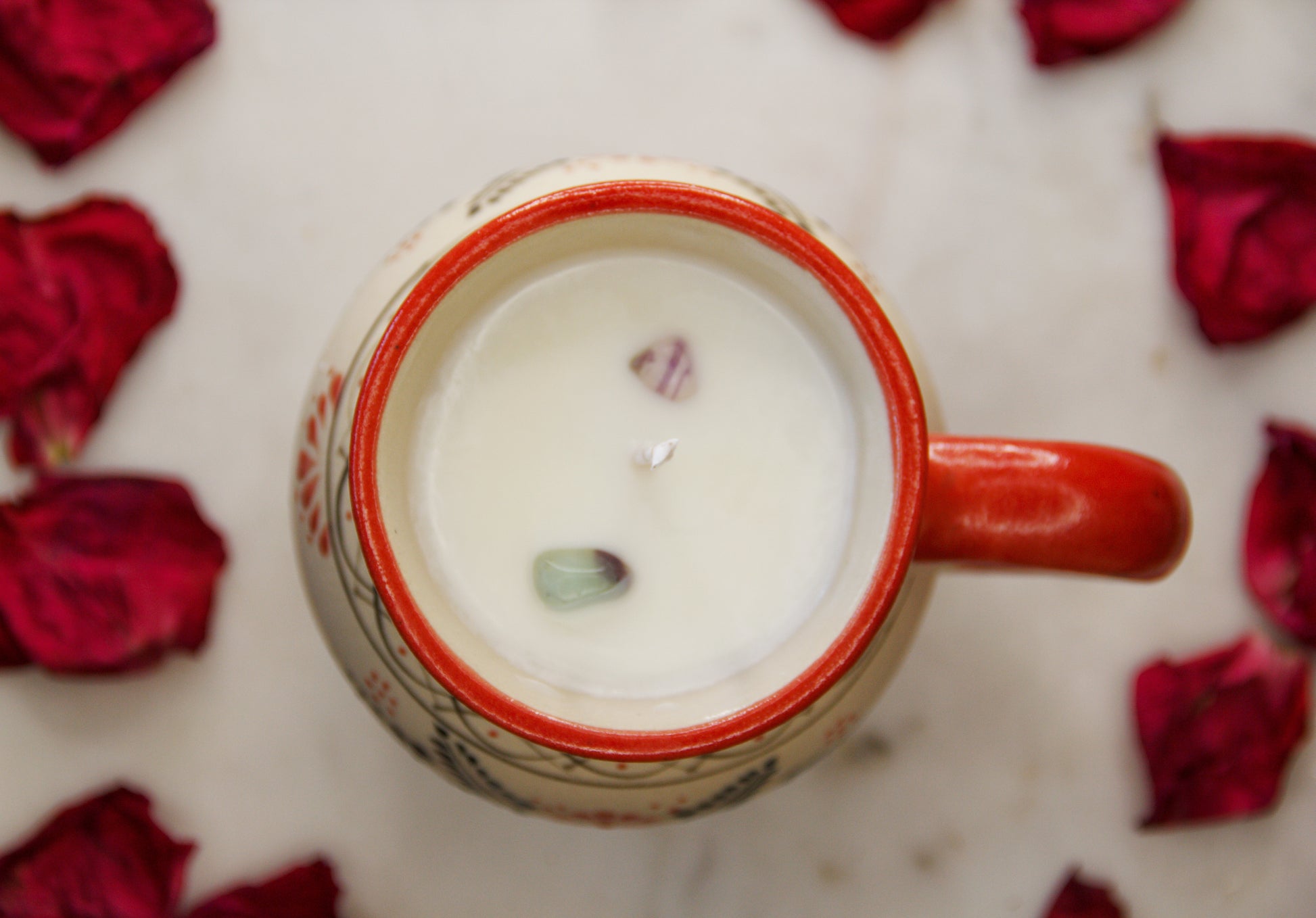 top view of a handmade artisanal candle in a red floral design mug with a handle. Custom made by Artisan in Mexico. 100% All Natural Soy Candle. Reuse the talavera as home decor or storage